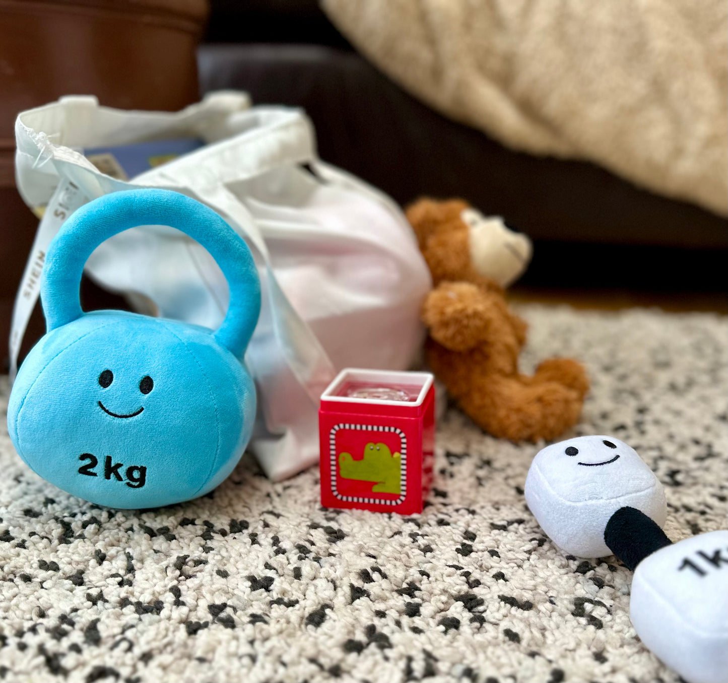 Mystic Blue kettlebell and Lamby Black and White dumbbell placed in a lounge, showcasing Hazza Toyz fitness-inspired toys designed for toddlers' active play at home.