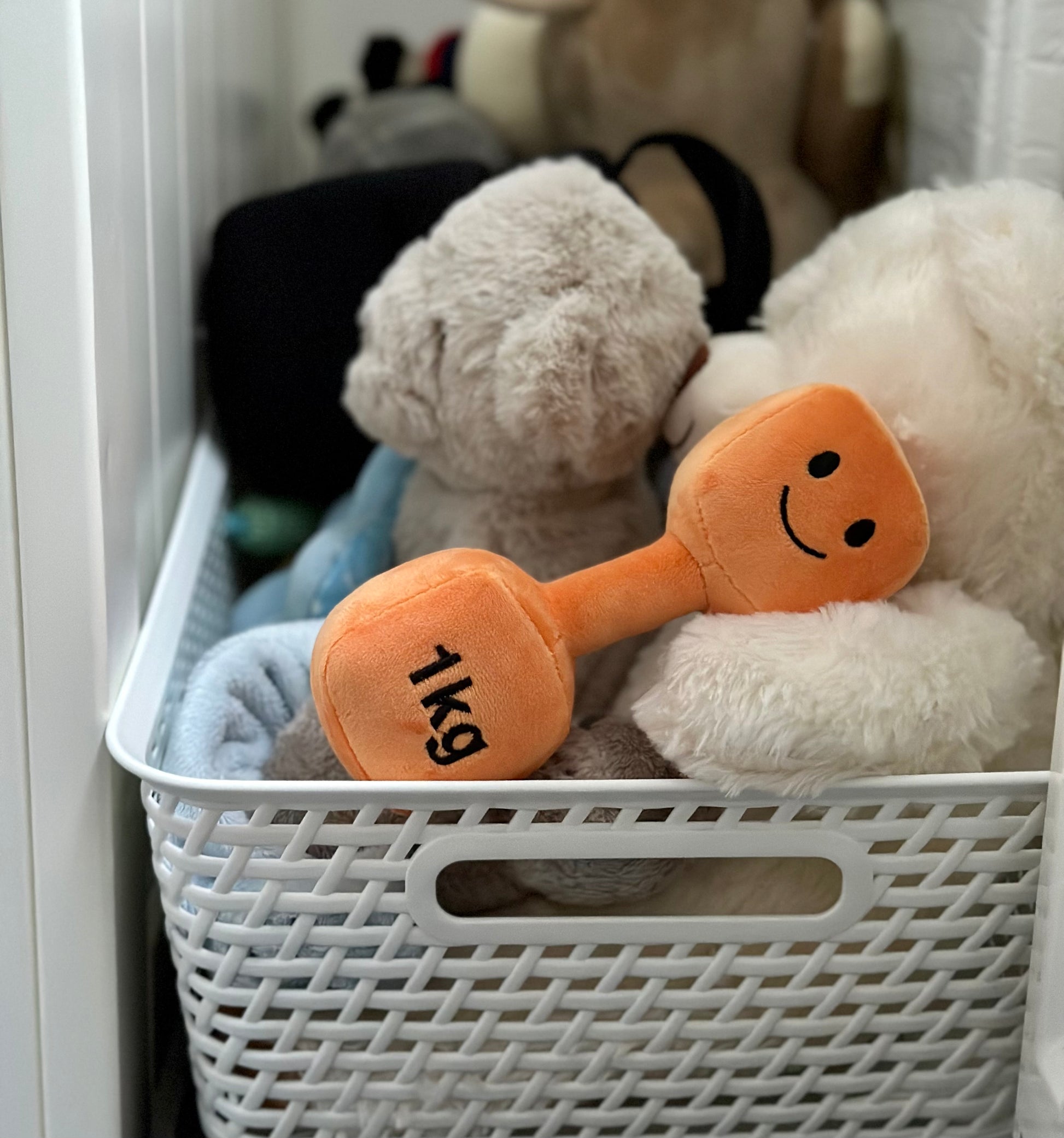 Hazza Toyz Apricot Orange dumbbell in a basket of toys, ready for playtime and sensory exploration