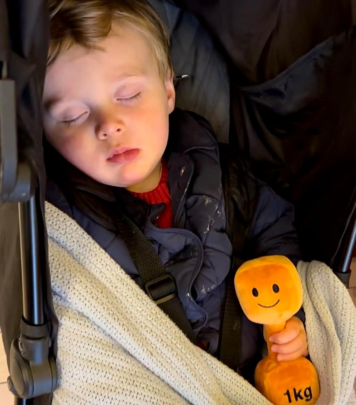 Baby asleep holding Hazza Toyz Apricot Orange plush dumbbell, providing comfort and sensory relaxation during naptime