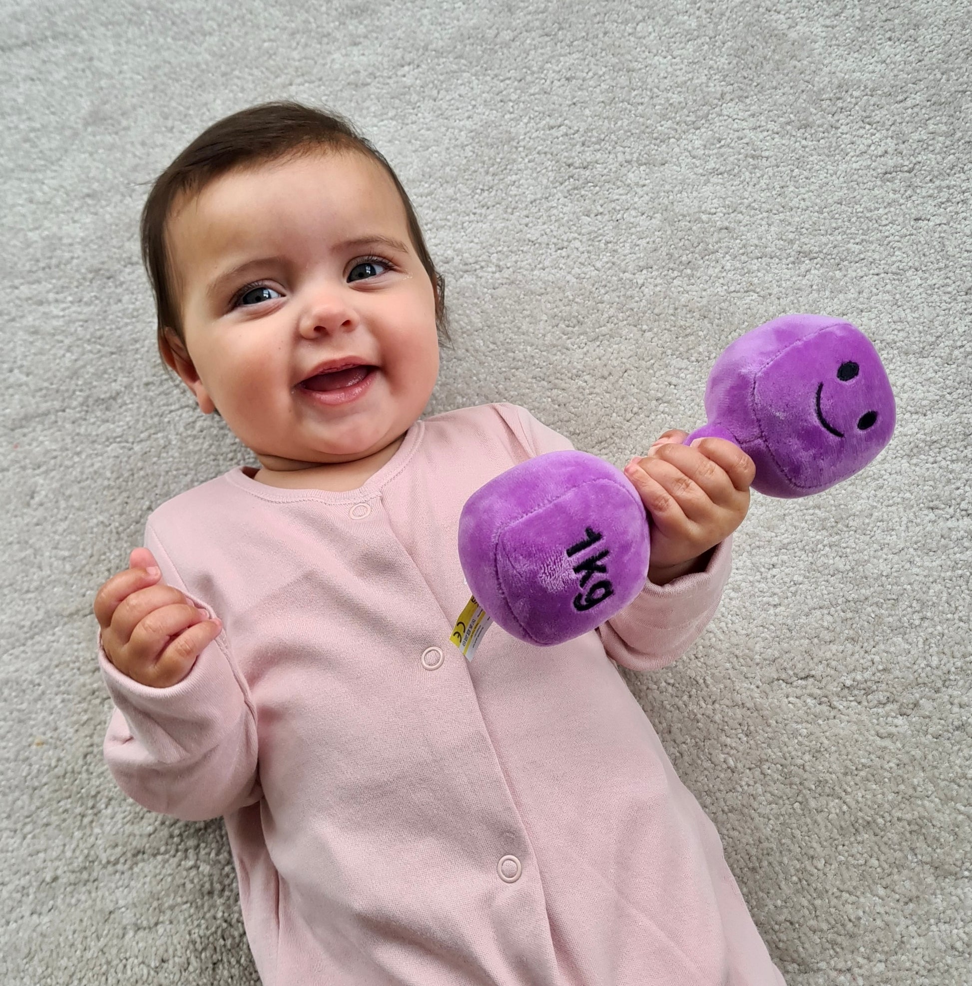 Baby gripping Hazza Toyz Lavender Purple dumbbell, engaging in sensory play and developing fine motor skills