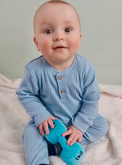 Baby holding Hazza Toyz dumbbell and looking at camera, enjoying playful interaction and sensory development