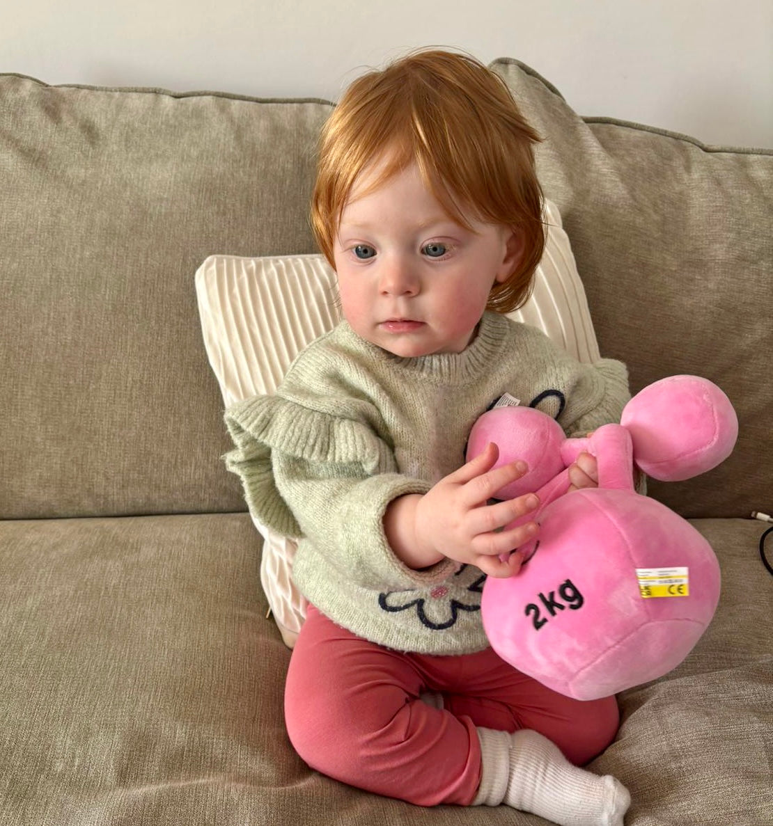 Baby hugging Hazza Toyz Candy Chateau Pink dumbbell and kettlebell, enjoying soft plush toys during playtime