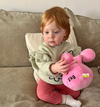 Baby hugging Hazza Toyz Candy Chateau Pink dumbbell and kettlebell, enjoying soft plush toys during playtime