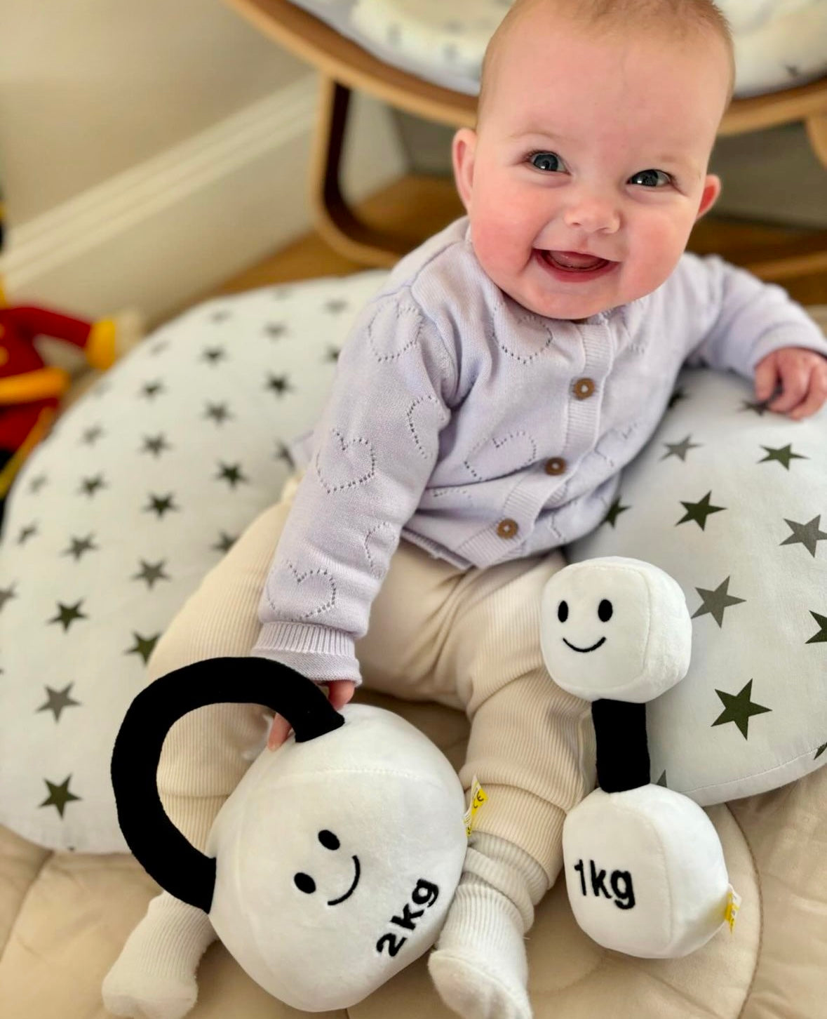 Baby smiling with Hazza Toyz Lamby Black and White dumbbell and kettlebell, enjoying playful interaction with soft plush toys