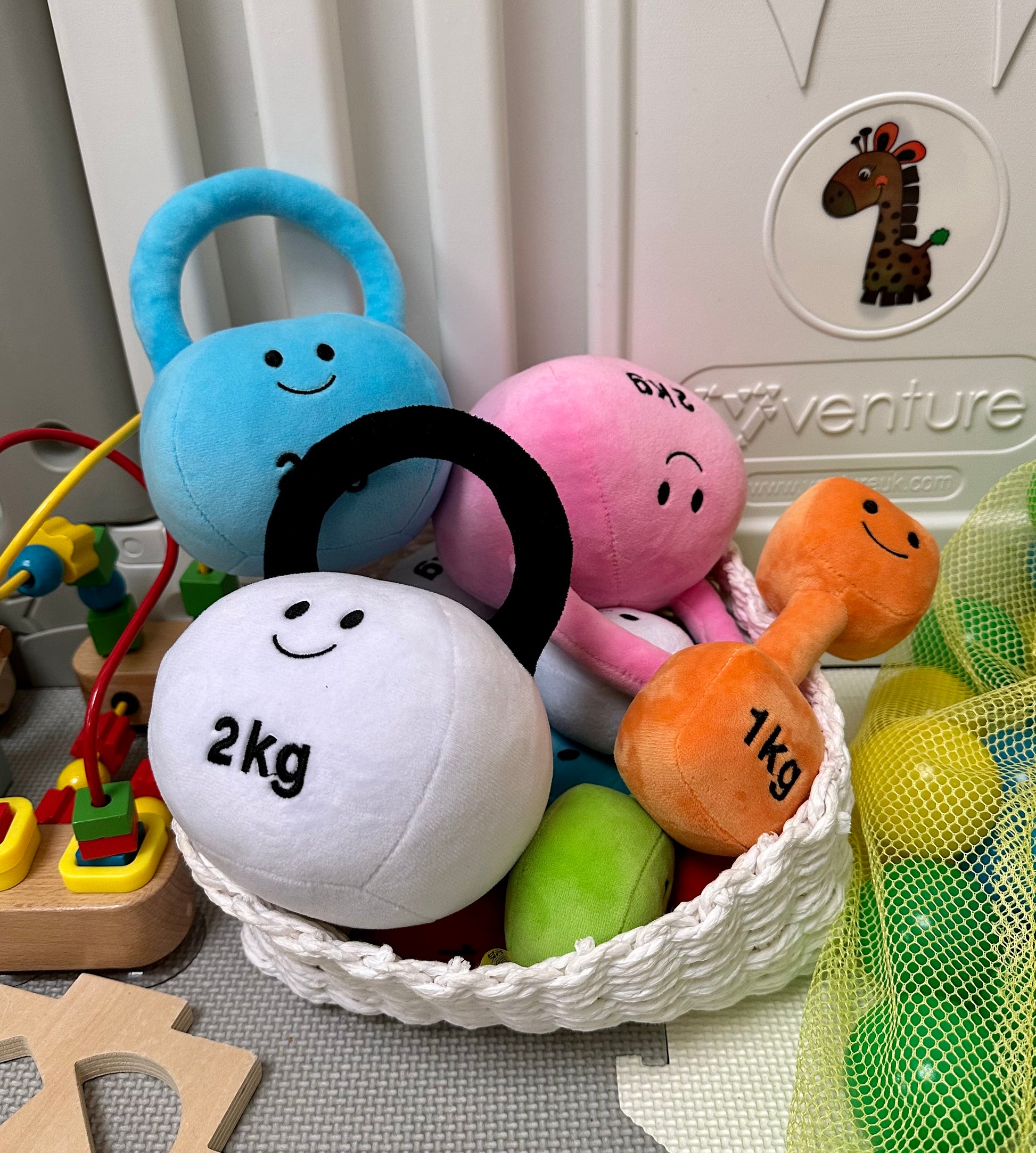 Basket filled with Hazza Toyz kettlebells and dumbbells, offering a variety of colourful plush toys for sensory play and motor skill development