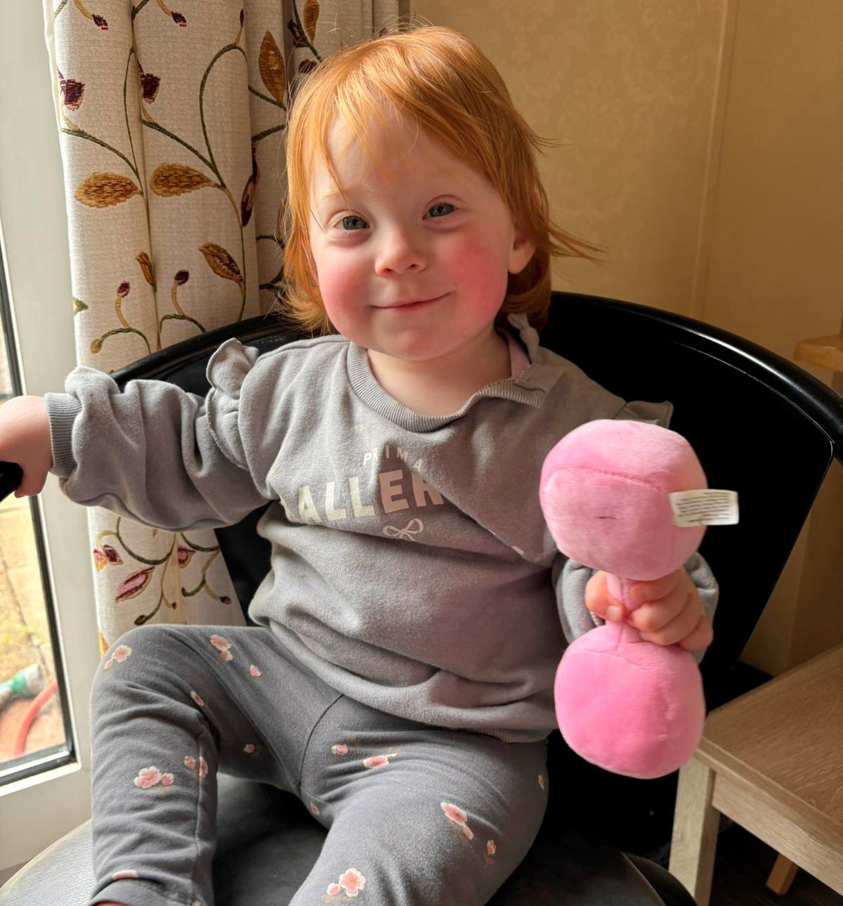 Smiling toddler holding Hazza Toyz Candy Chateau Pink dumbbell, enjoying playful interaction and sensory development