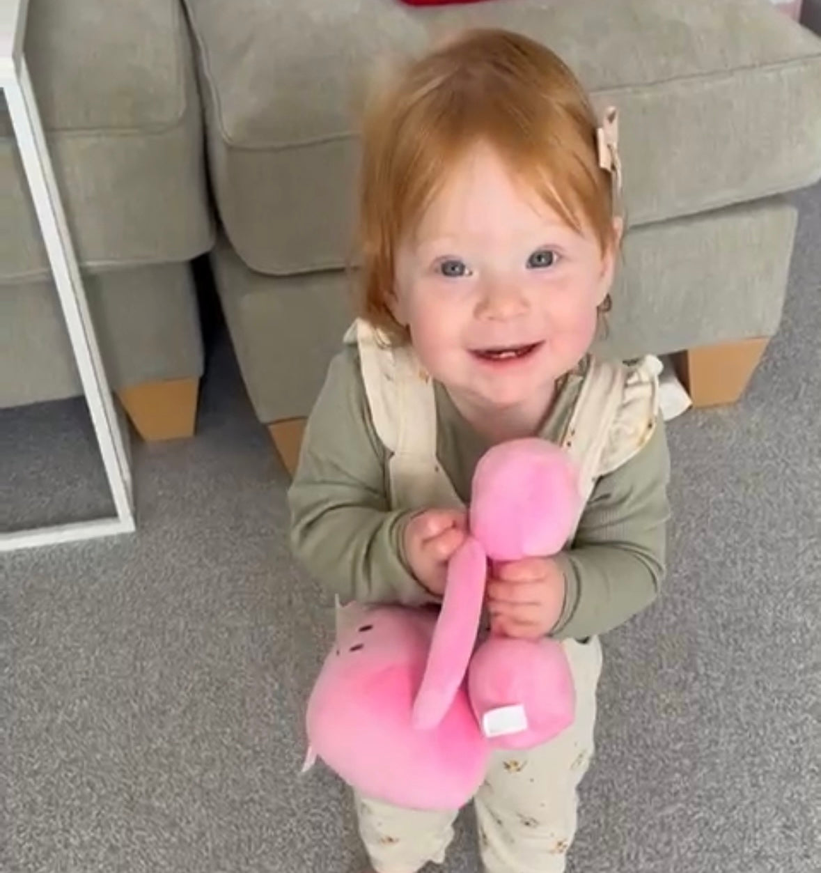 Cute toddler holding Hazza Toyz Candy Chateau Pink dumbbell and kettlebell, smiling at camera, enjoying playful sensory interaction