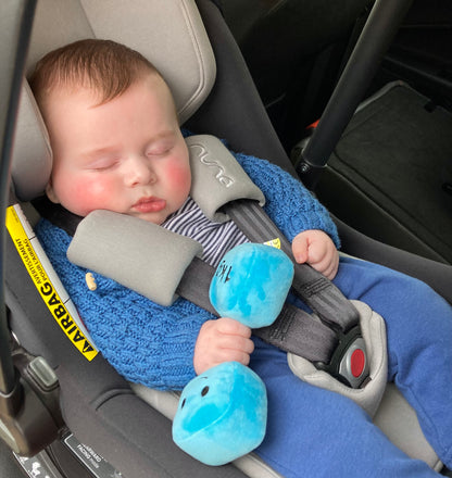 Newborn baby asleep in car seat, holding Hazza Toyz Mystic Blue dumbbell, enjoying a cosy and comforting nap during travel