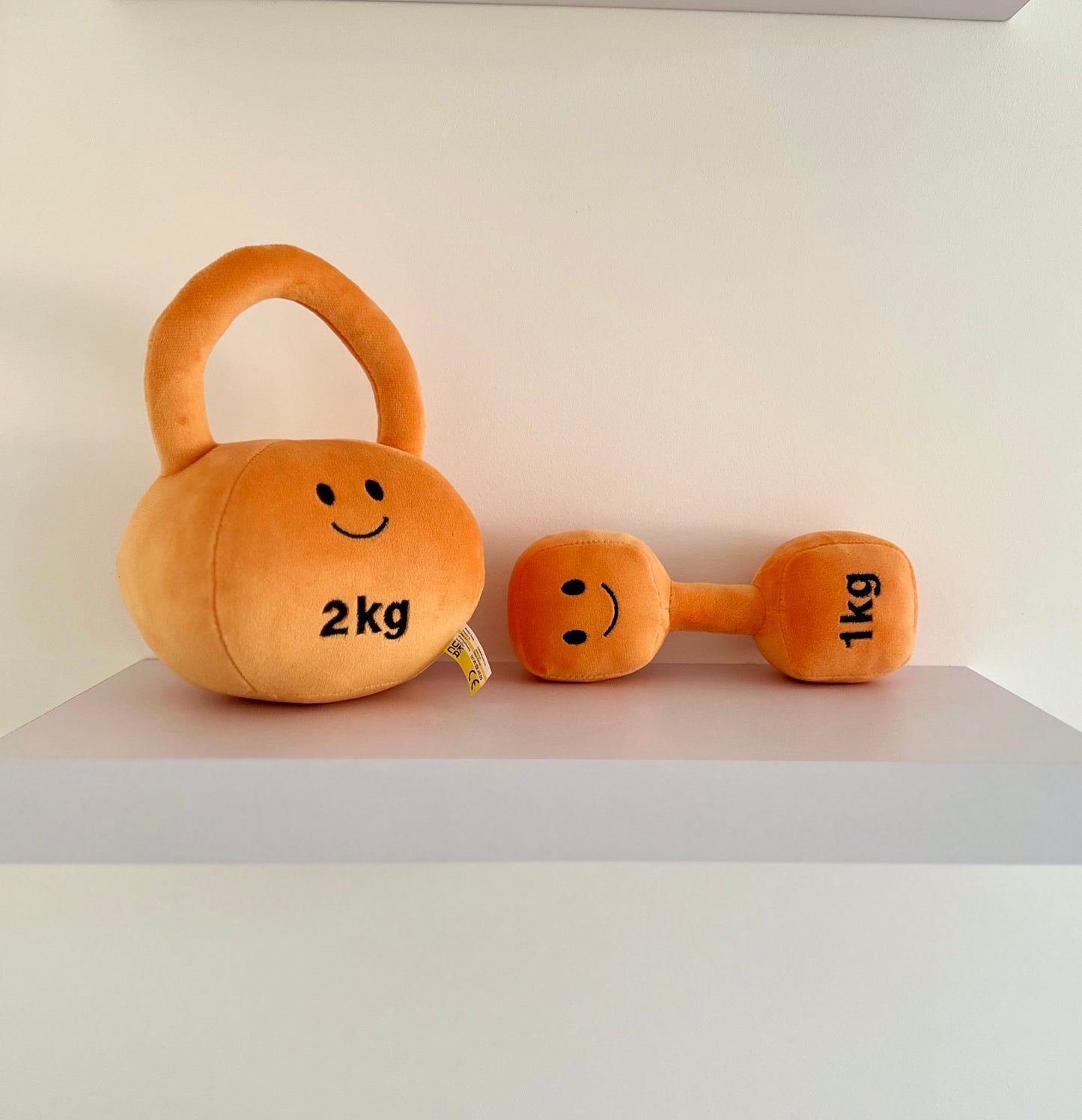 Hazza Toyz Apricot Orange kettlebell and dumbbell on shelf, adding a colourful and playful touch to nursery decor