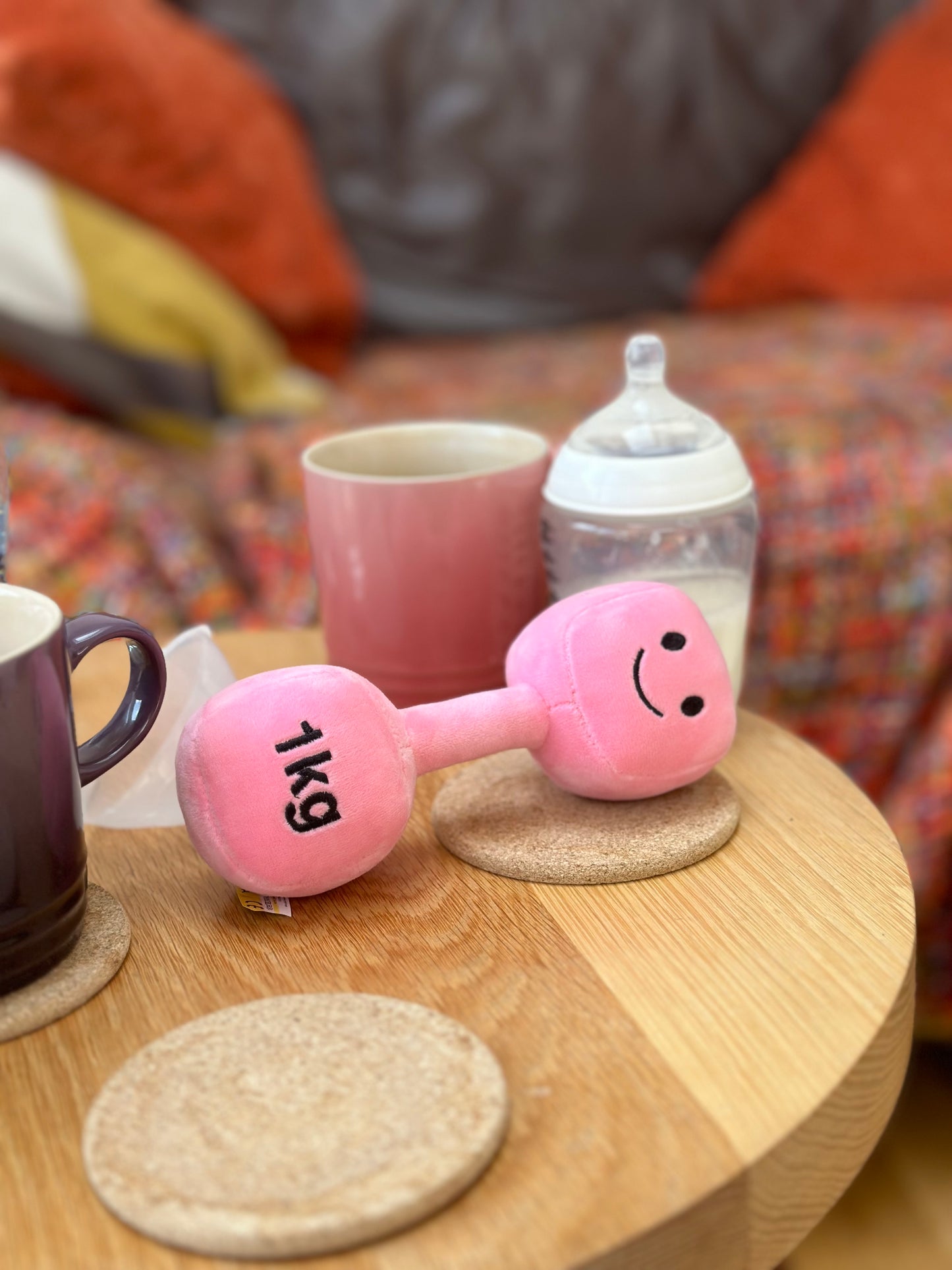 Hazza Toyz Candy Chateau Pink dumbbell on table next to a milk bottle and coffee cups, creating a cosy scene for playful moments