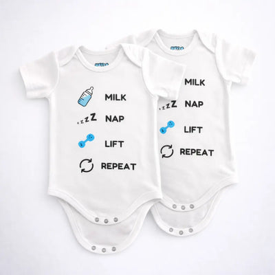 Two white and blue baby bodysuits with milk nap lift repeat text and small bottle and dumbbell graphics displayed on a grey background