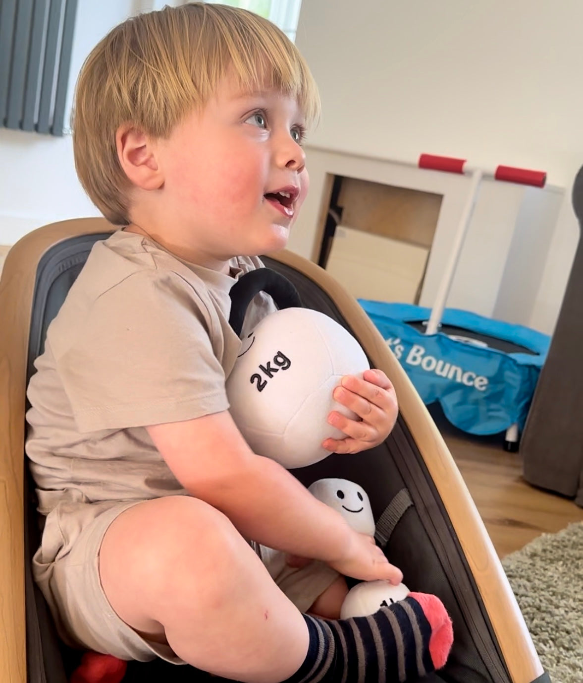 oddler cuddling Hazza Toyz Lamby Black and White plush dumbbell and kettlebell, enjoying sensory comfort and interactive play