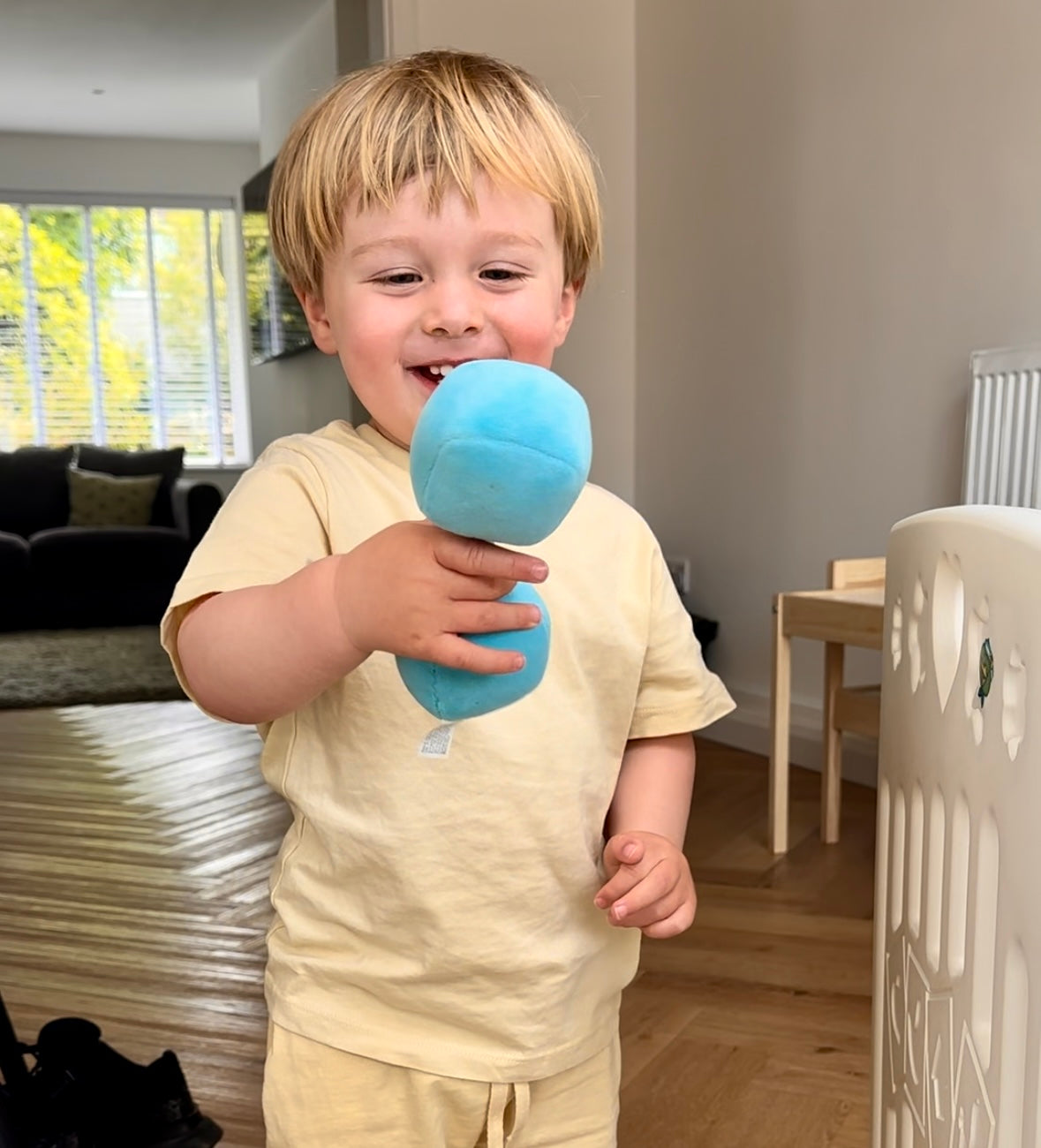 Toddler smiling at Hazza Toyz Mystic Blue plush dumbbell, engaging in playful interaction and sensory development