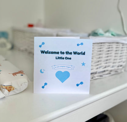 Welcome to the World blue baby shower card displayed in baby room, celebrating the arrival of a new baby with a warm message