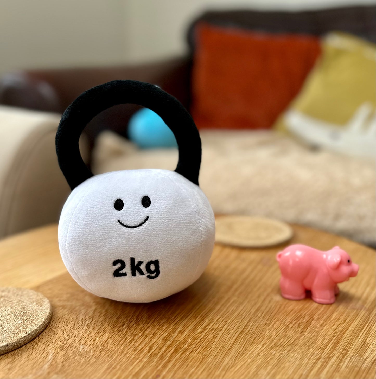 Hazza Toyz Lamby Black and White kettlebell on table with pink toy pig next to it, creating a playful scene for toddlers' sensory exploration