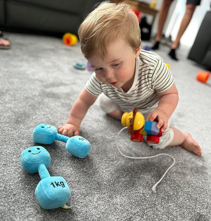 Baby crawling towards two Mystic Blue dumbbells, showing curiosity and active play with Hazza Toyz fitness-inspired toys for toddlers.