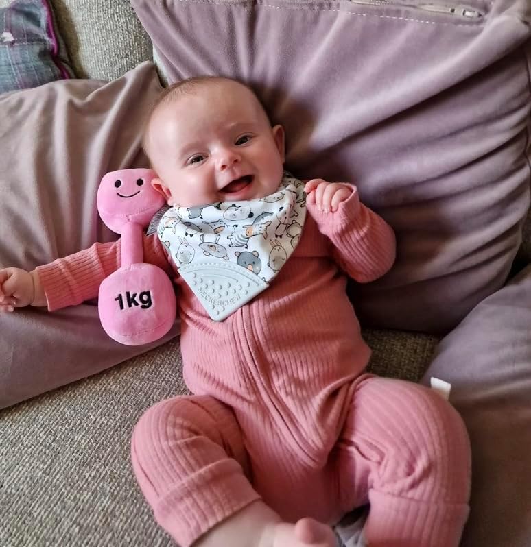 Baby girl wearing a cute bib and holding a Candy Chateau Pink dumbbell, enjoying a playful moment with Hazza Toyz fitness-inspired toys for toddlers.