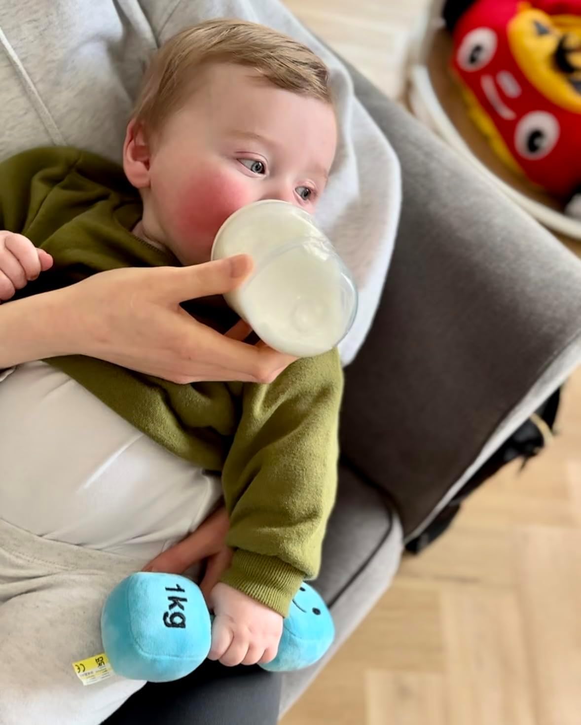 Baby sipping on milk while holding a Mystic Blue dumbbell, blending comfort and play with Hazza Toyz fitness-inspired toys for toddlers.