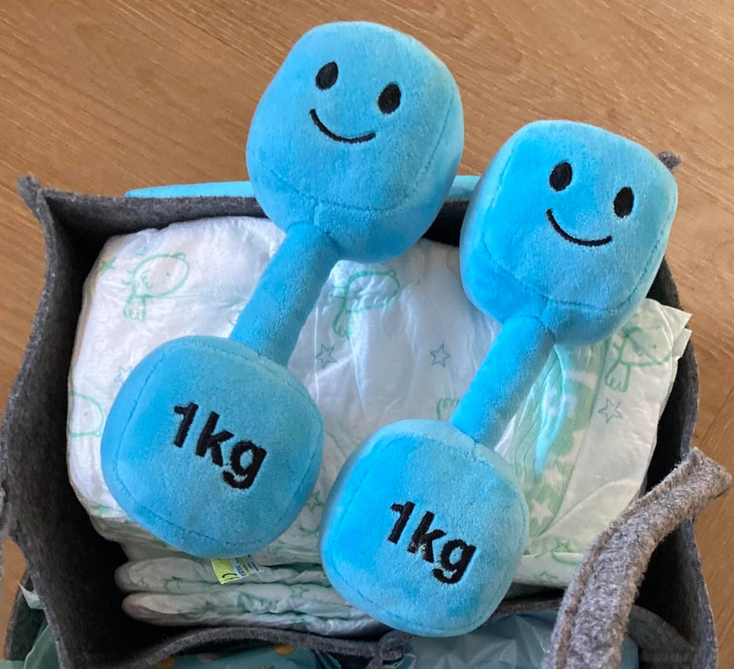 Double pack of Mystic Blue dumbbells placed on a bag filled with baby essentials, highlighting the convenience and portability of Hazza Toyz fitness-inspired toys for toddlers.