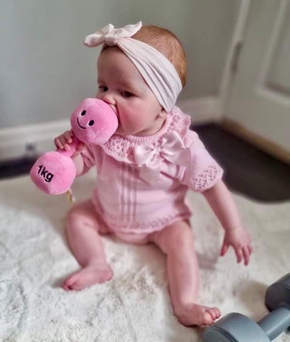 Candy Chateau Pink dumbbell held in the hands of a baby girl, showcasing early play and engagement with Hazza Toyz fitness-inspired toys for toddlers.