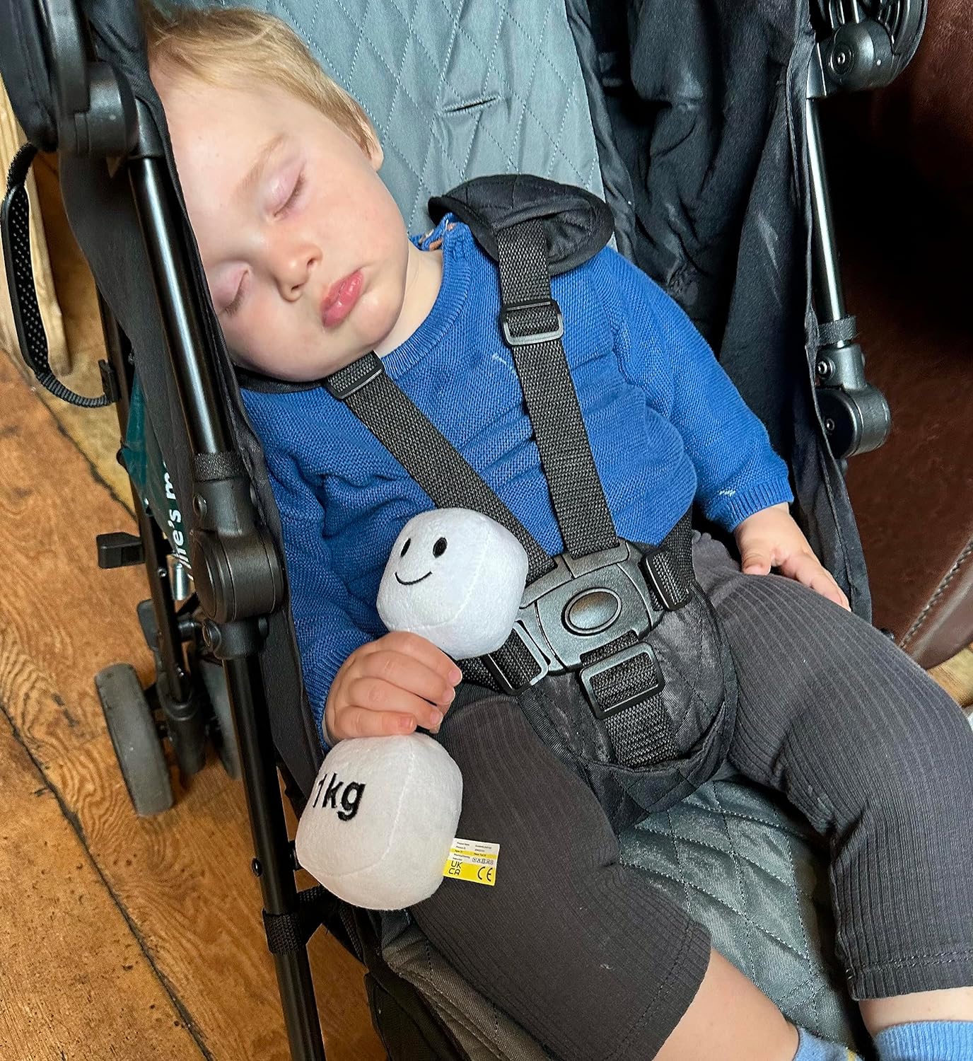 Cute toddler asleep in a coffee shop, holding a Lamby Black and White dumbbell, capturing a peaceful moment with Hazza Toyz fitness-inspired toys for toddlers.