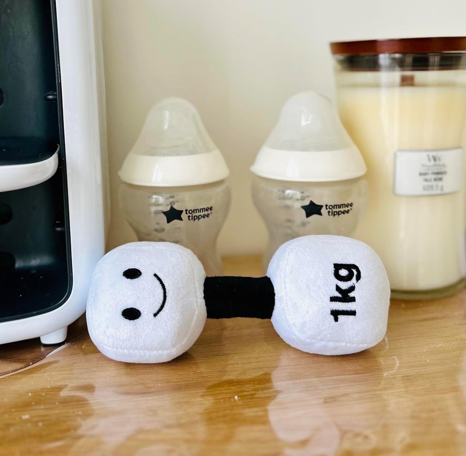 Lamby Black and White dumbbell placed next to a milk bottle and milk powder, illustrating a blend of everyday baby essentials and Hazza Toyz fitness-inspired toys for toddlers.