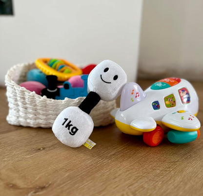 Lamby Black and White dumbbell placed among other baby toys, showcasing a playful selection of Hazza Toyz fitness-inspired toys for toddlers.