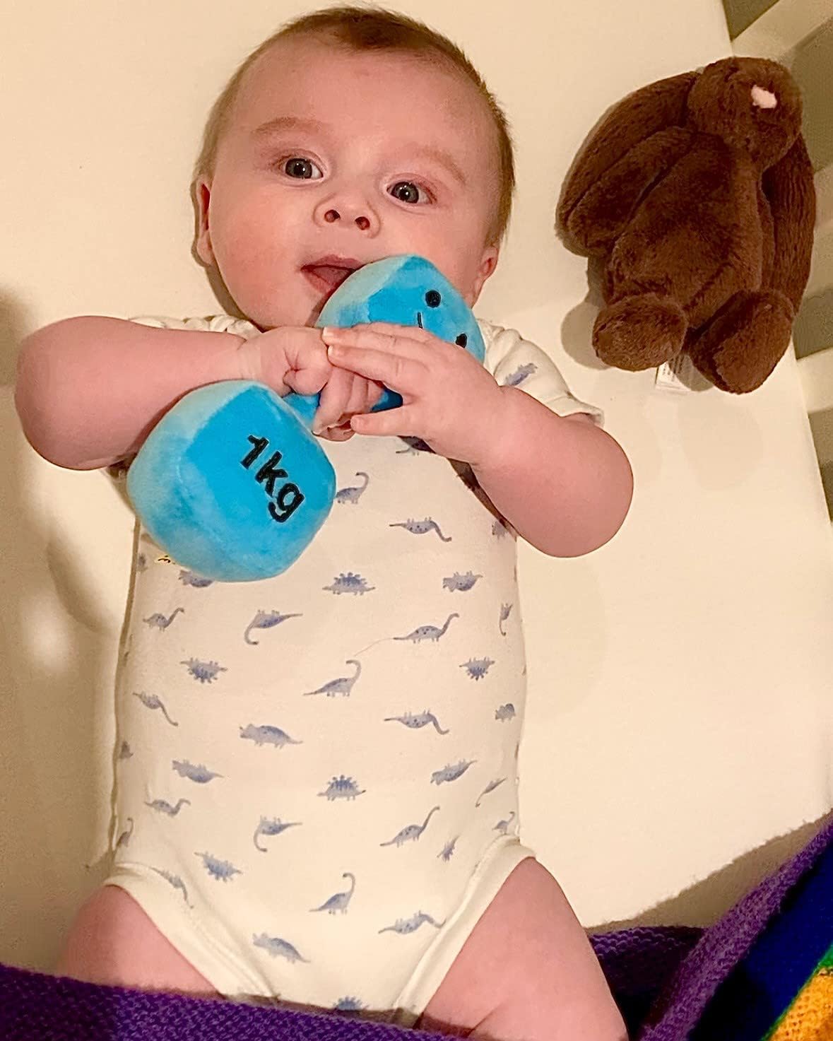 Young baby cuddling a Mystic Blue dumbbell, enjoying a cosy and comforting moment with Hazza Toyz fitness-inspired toys for toddlers.